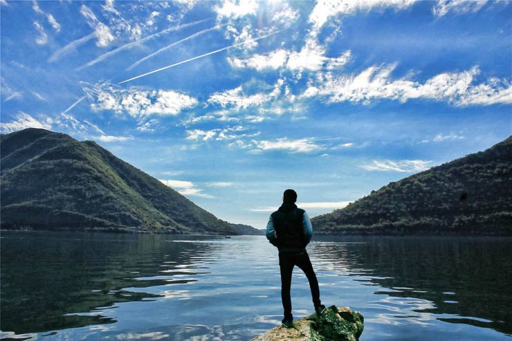 Solitary nature sky river lake water mountain mountains man stand standing alone lonely