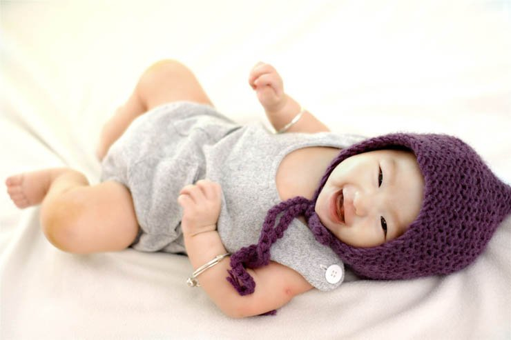 adorable baby laying down happy wearing hat