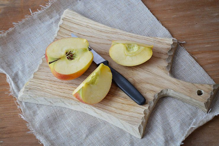 an apple cut on kitchen table with knife