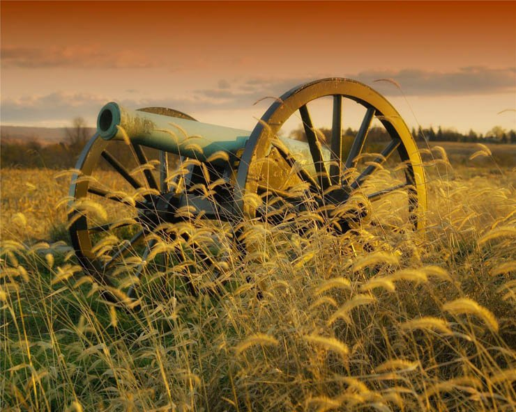 ancient vintage cannon around field of barley sunset
