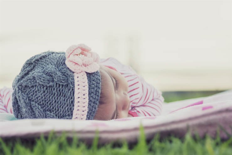 baby with hat sleeping on grass