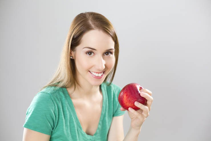 pretty girl happily holding red apple