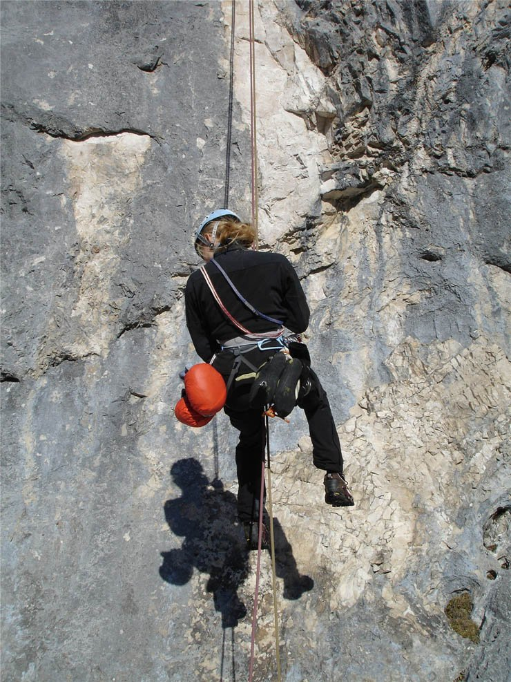 woman wearing black climbing mountain with rope