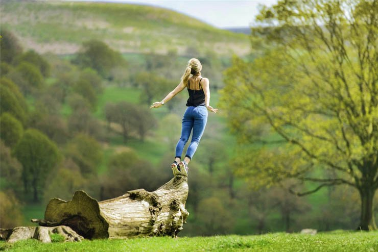 young adult girl standing tree trunk nature forest sunny enjoy brave
